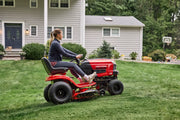 Photo of Craftsman riding lawn mower CM13BL78XTA93 in use on a grassy yard near a house.