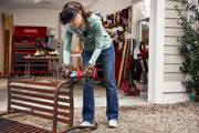 Photo of CRAFTSMAN CMCG452B cordless grinder cutting metal bench outdoors, with safety gear and tools visible.