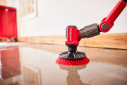Photo of Craftsman CMCPSMB power scrubber with red brush head cleaning a wet floor, close-up angle.
