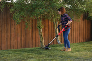 Person using Craftsman string trimmer CMCST900B to cut grass near trees in a backyard, product in use outdoors.