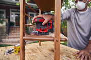 Photo of a person using a Craftsman cordless sander CMCW222B on a wooden chair, outdoor workspace.