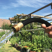 Photo of Craftsman garden hose CMXMHHF5850L with brass connector, water flowing, outdoor garden background.